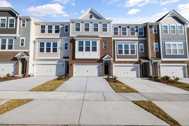 Home Row of modern townhouses with spacious driveways and garage fronts under blue sky.
