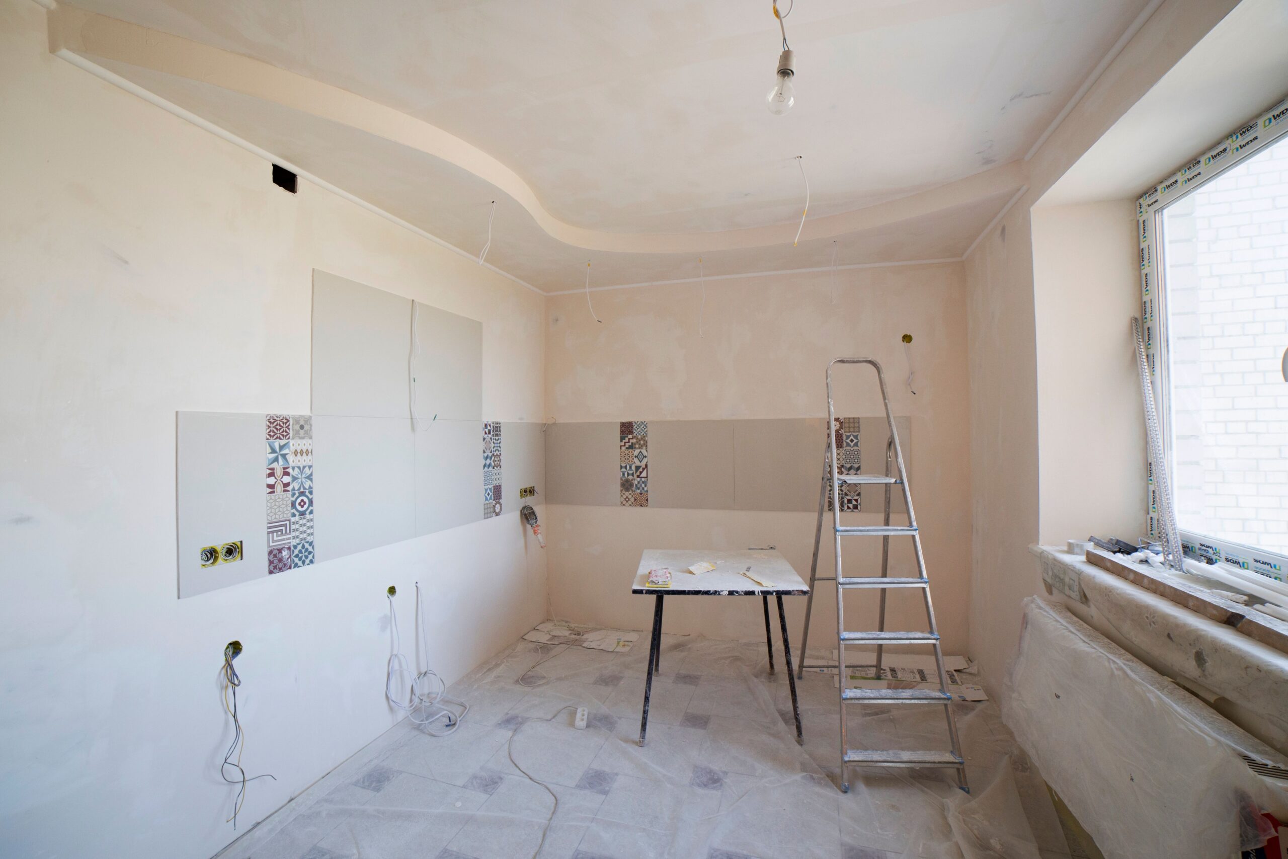 Home Spacious kitchen under renovation with ladder and tools, showcasing a fresh new design.
