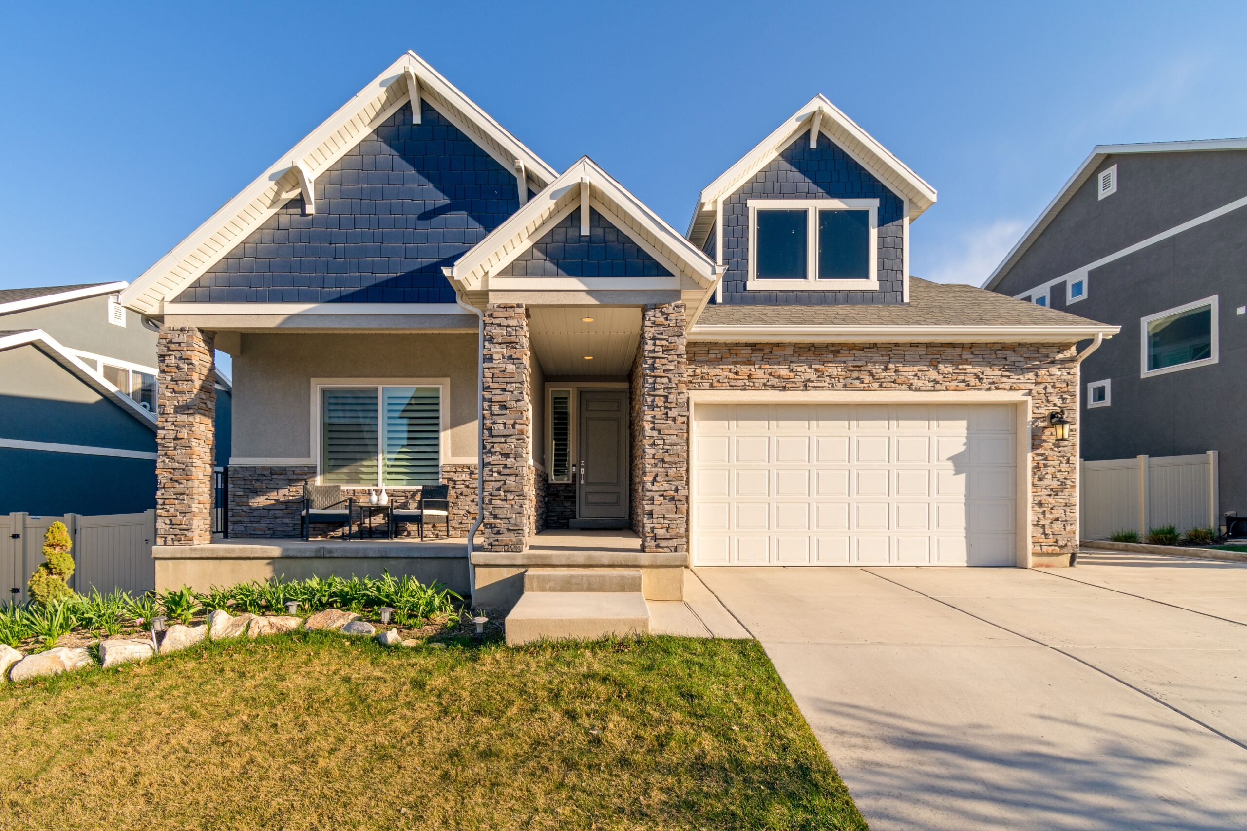 Home A charming modern suburban home with a stone facade and a neatly maintained lawn.