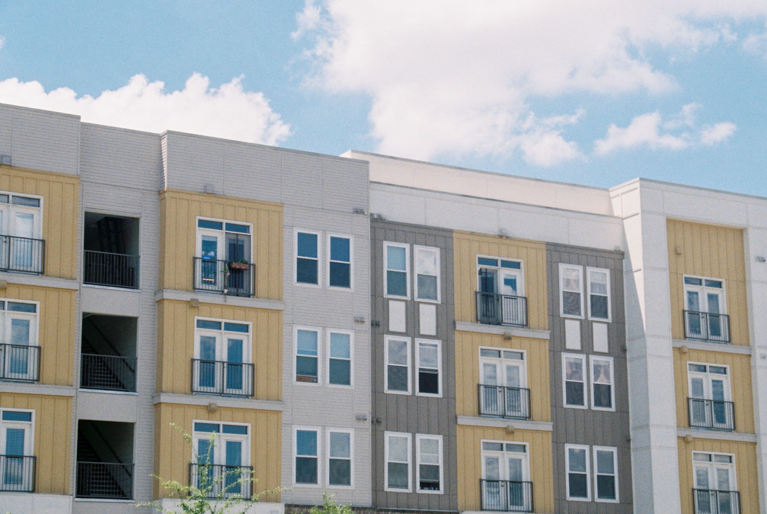 Home Contemporary apartment building exterior with yellow and grey panels under a clear blue sky.